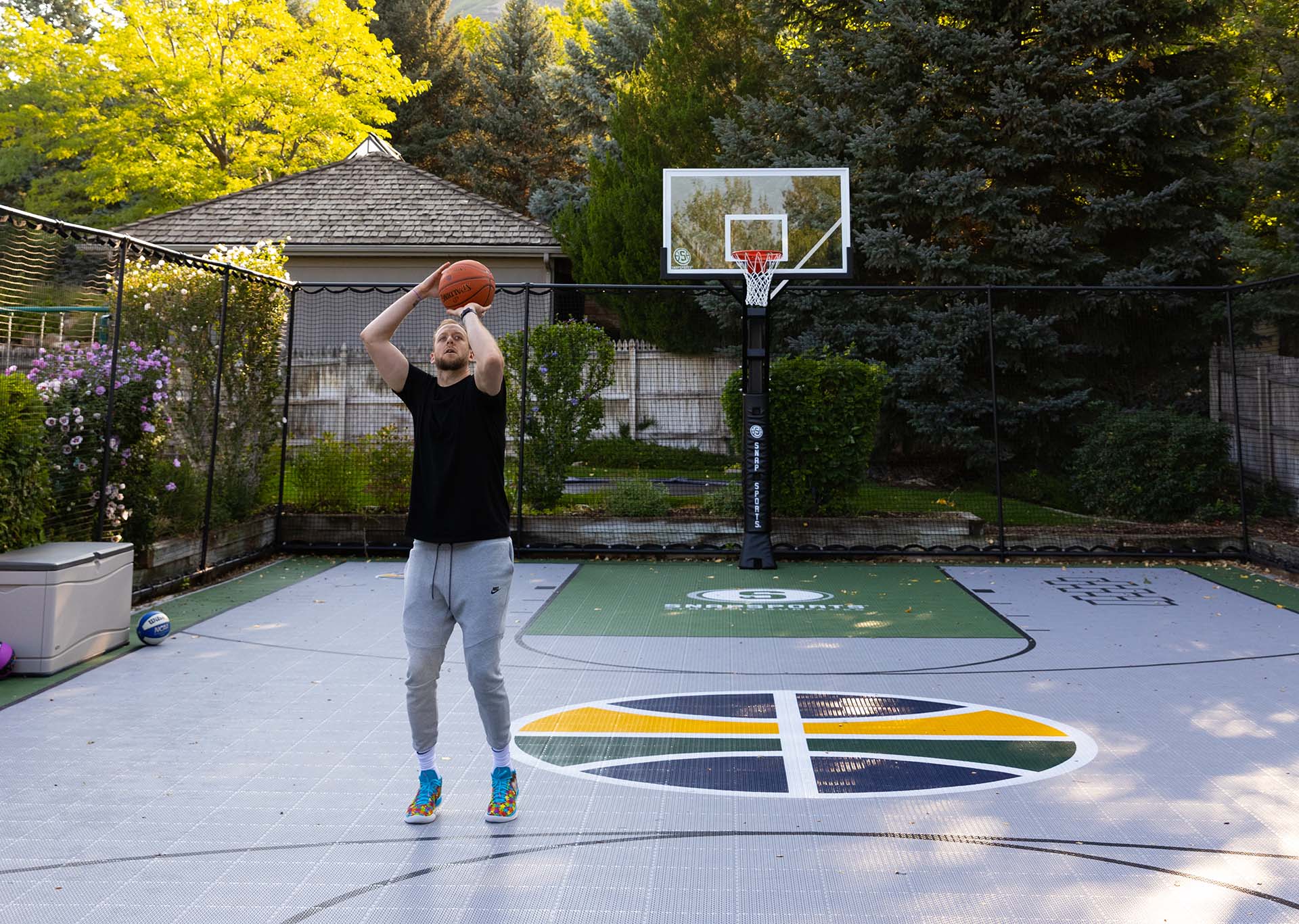 Joe ingles shooting a basketball on a Utah Jazz themed outdoor court